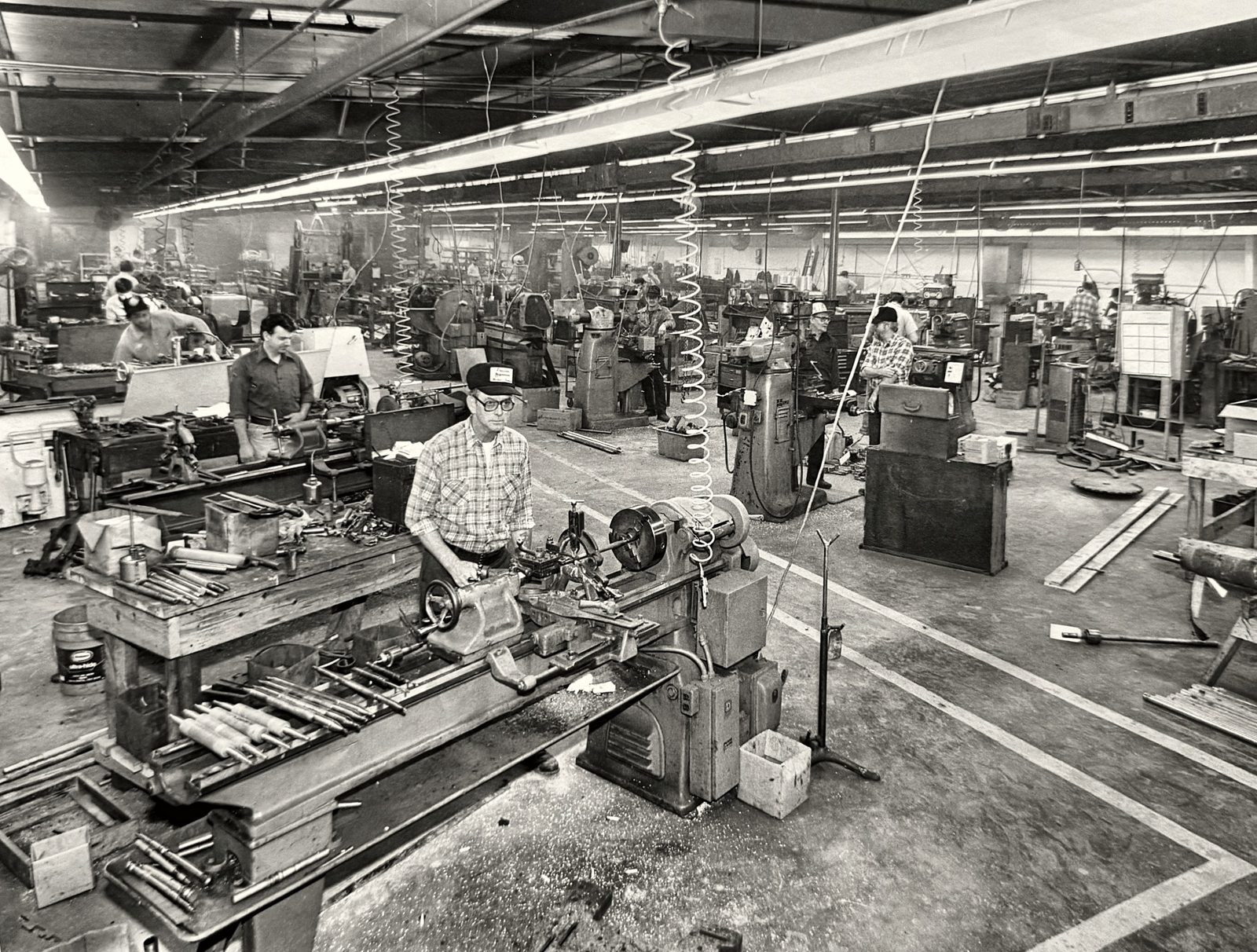 Vintage black and white photo of Precision Machine Products machinists at rows of lathes and mills