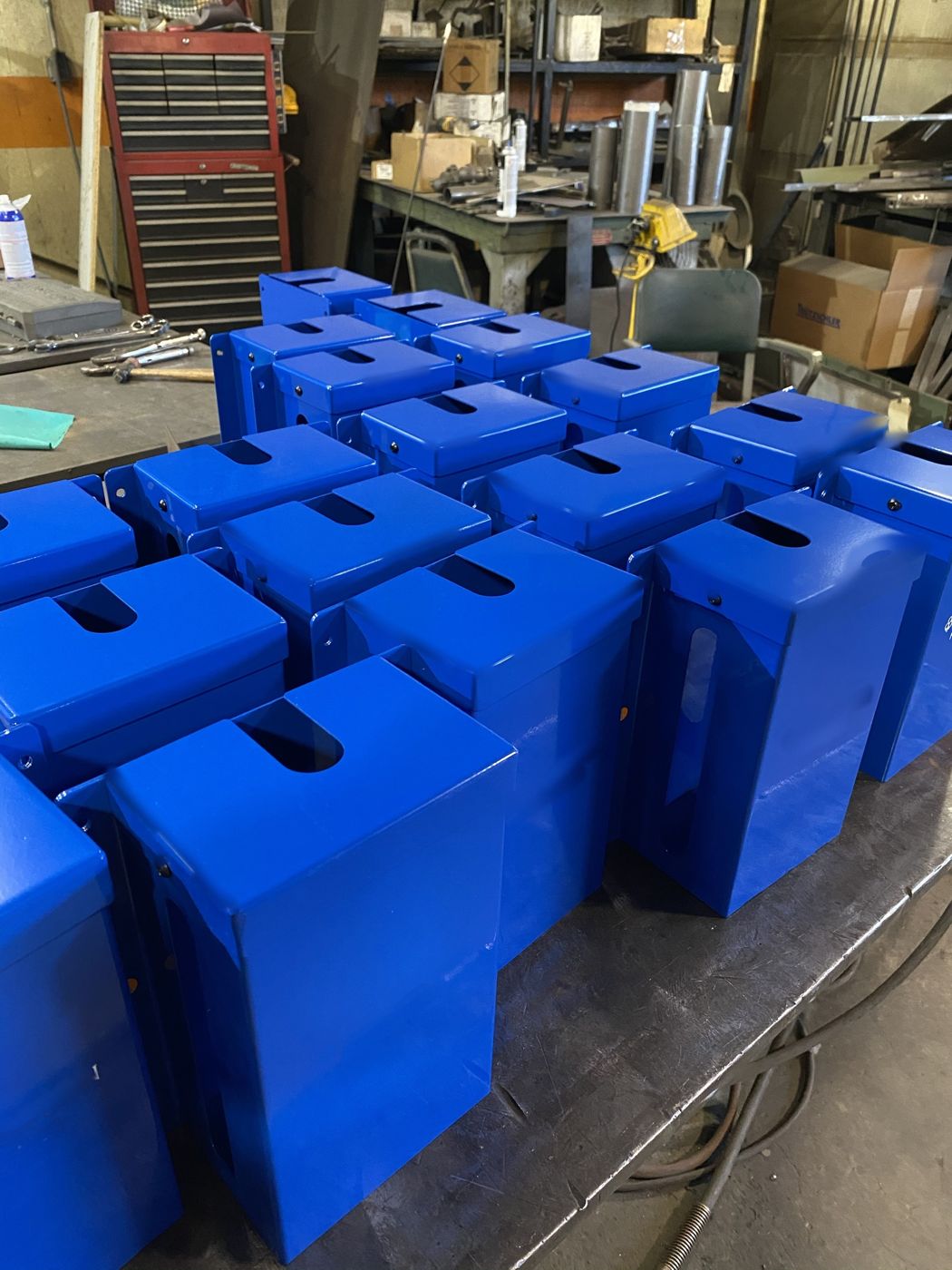 A table of blue powder-coated sheet metal boxes