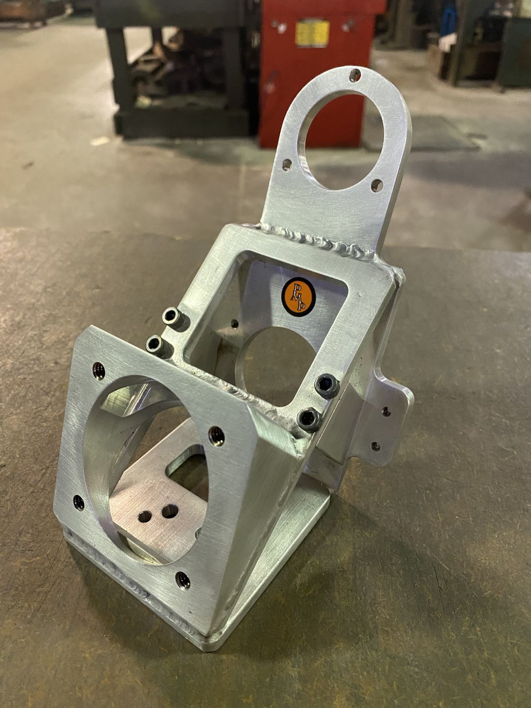 A welded aluminum mounting bracket with the PMP sticker