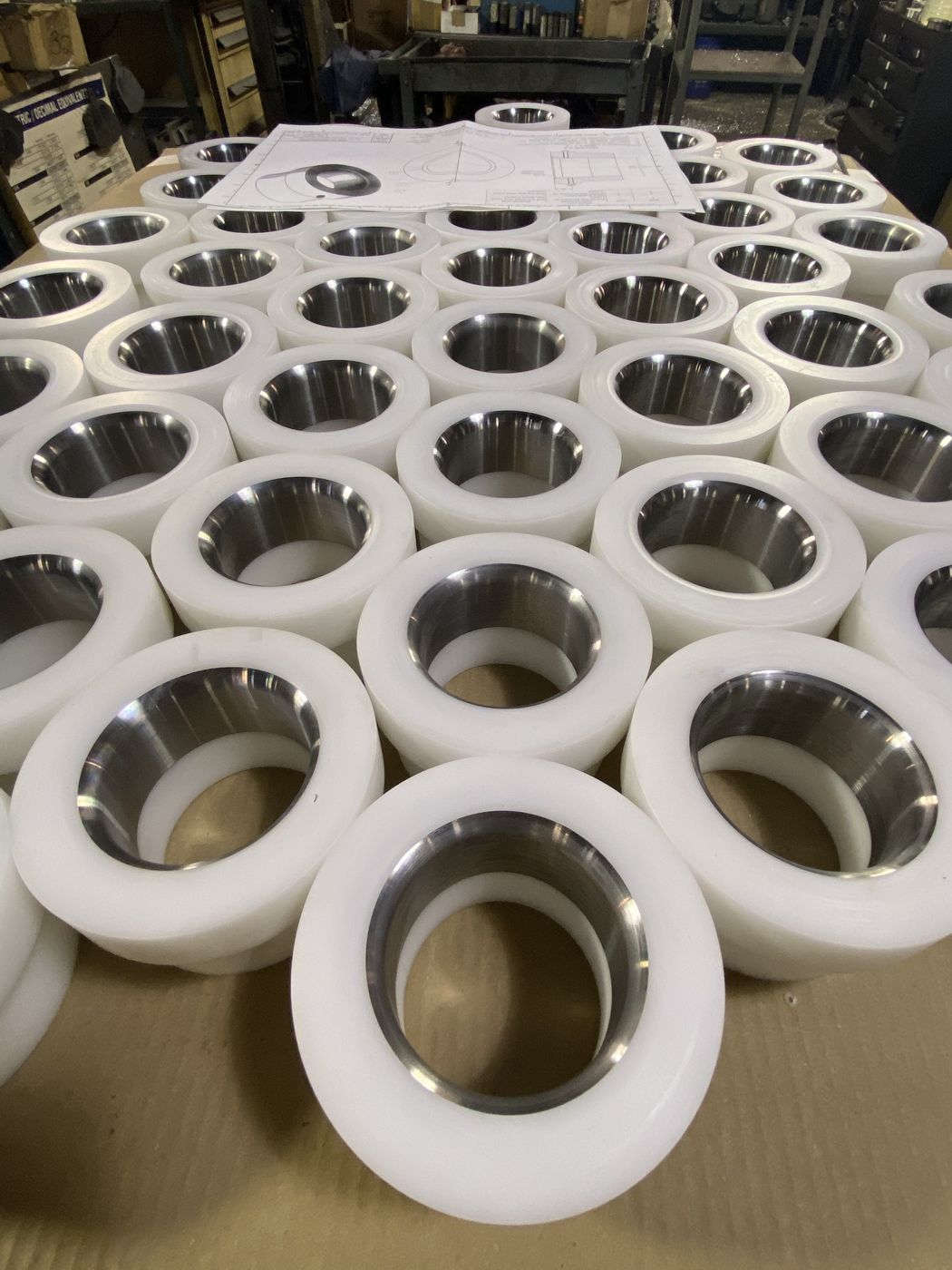 Finished white plastic rollers with steel inserts, laid out under the customer’s drawing